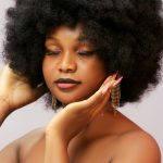 Studio portrait of a stylish woman with afro hair and glamorous makeup.